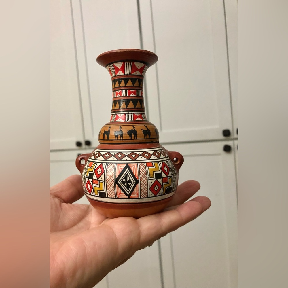Hand-painted Peruvian vase featuring traditional Inca-style, decorative llamas